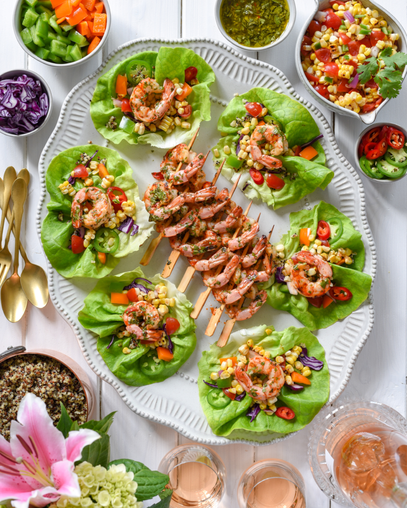A platter of shrimp lettuce wraps and chimichurri shrimp skewers. 