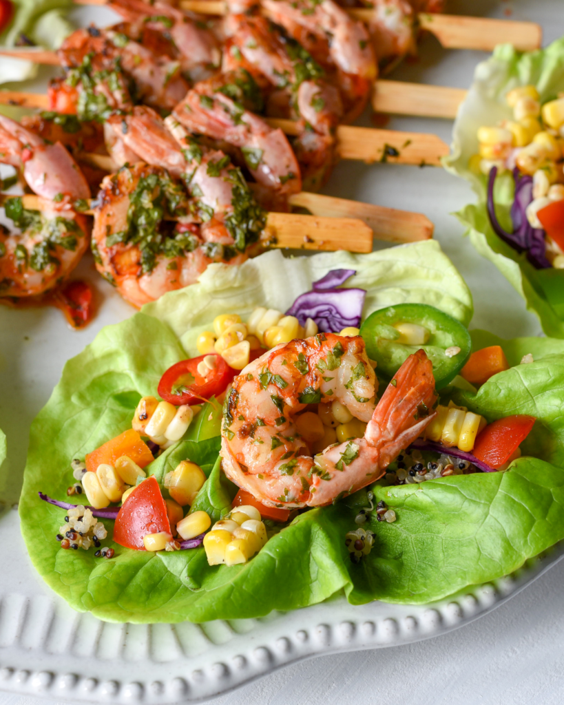 An individual shrimp lettuce wrap with corn salsa and chimichurri.