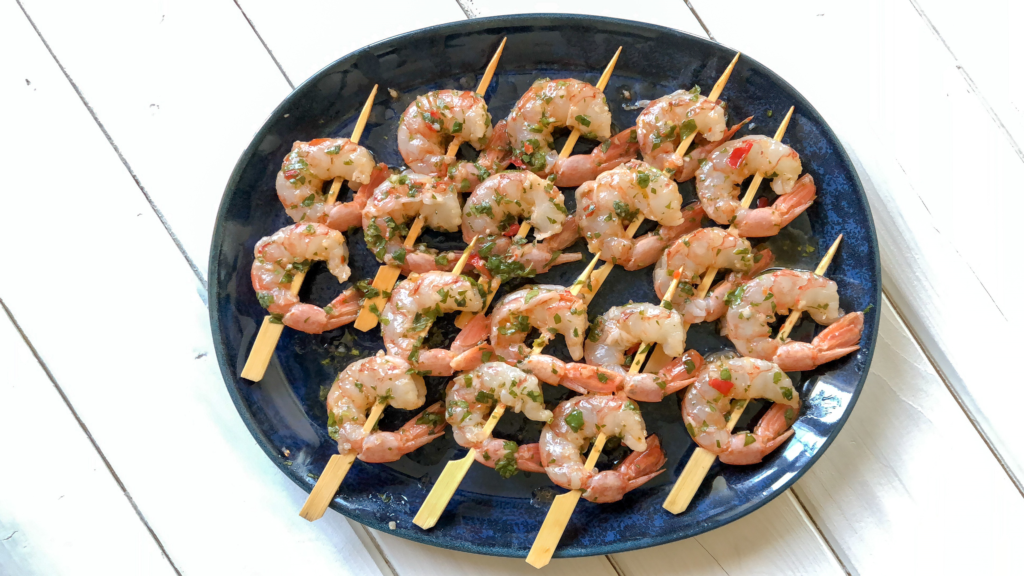 Shrimp marinated with Chimichurri on wooden skewers ready to be grilled.