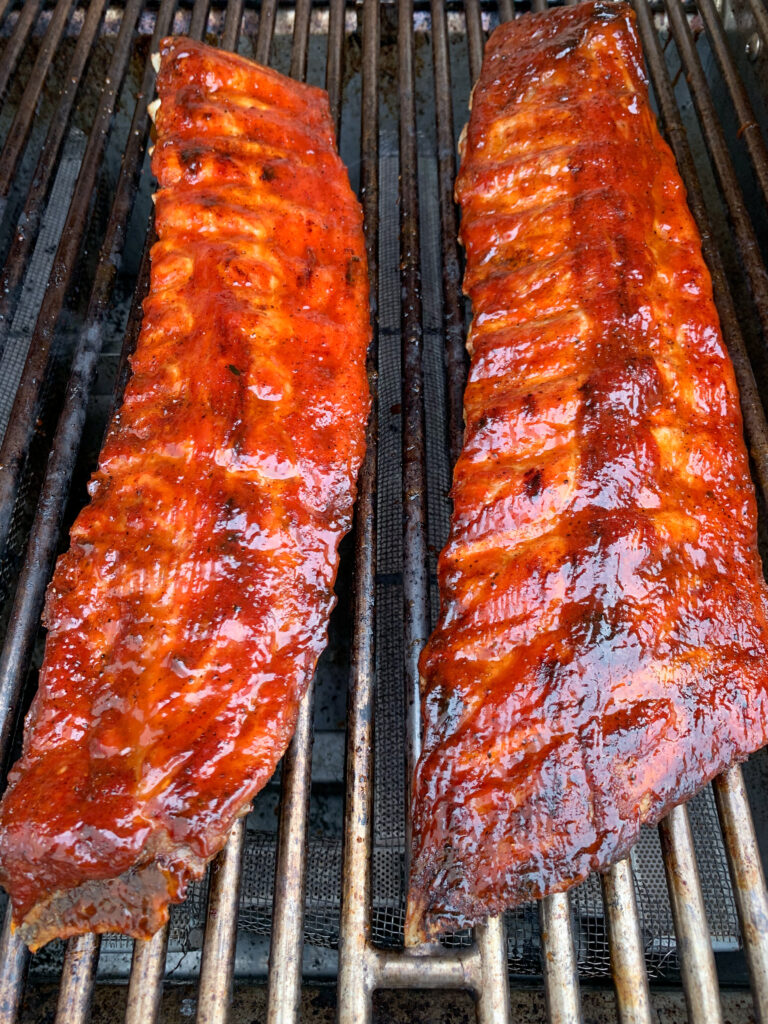 Two racks of glisening ribs on the barbeque. 