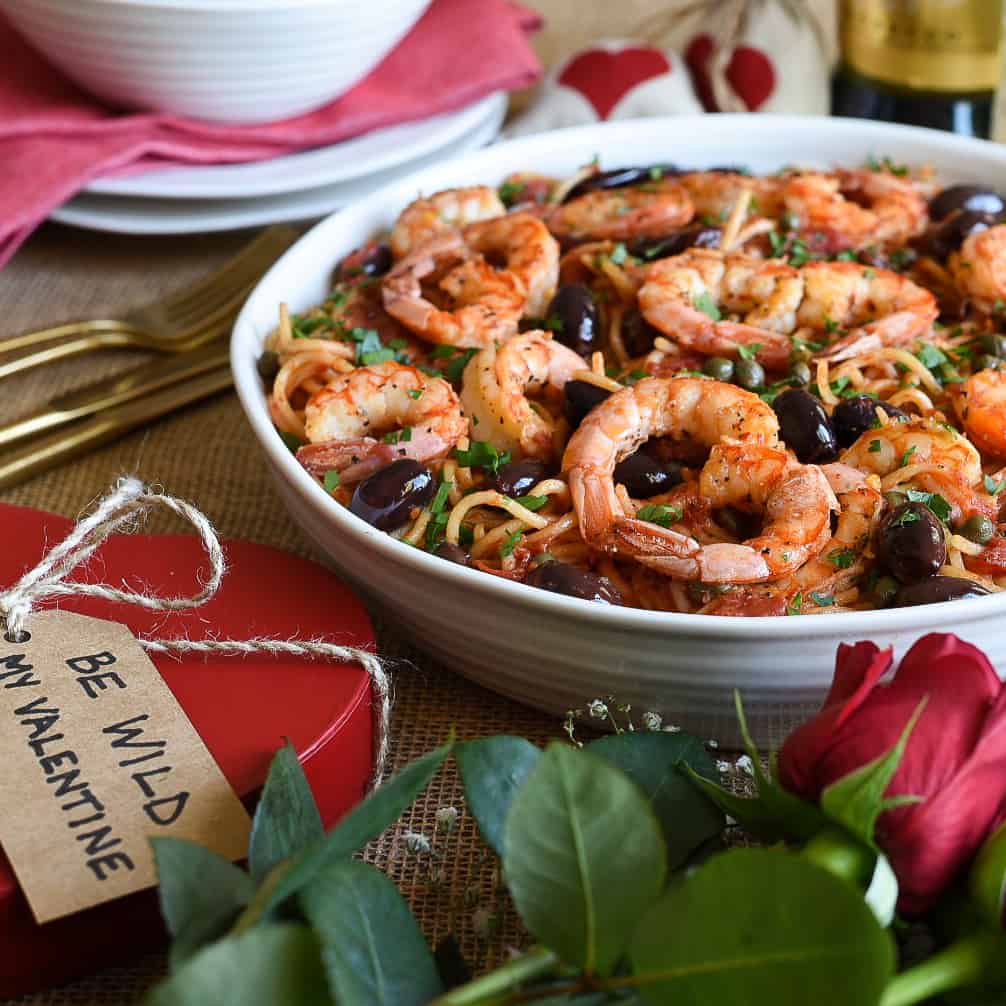 A Valentine's day meal of wild shrimp puttenesca with a box of chocolates and roses. 