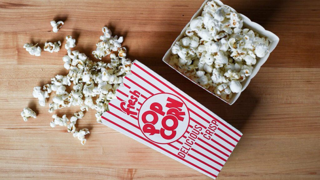 Two popcorn containers: one top down, and one is on it side with popcorn falling out. 