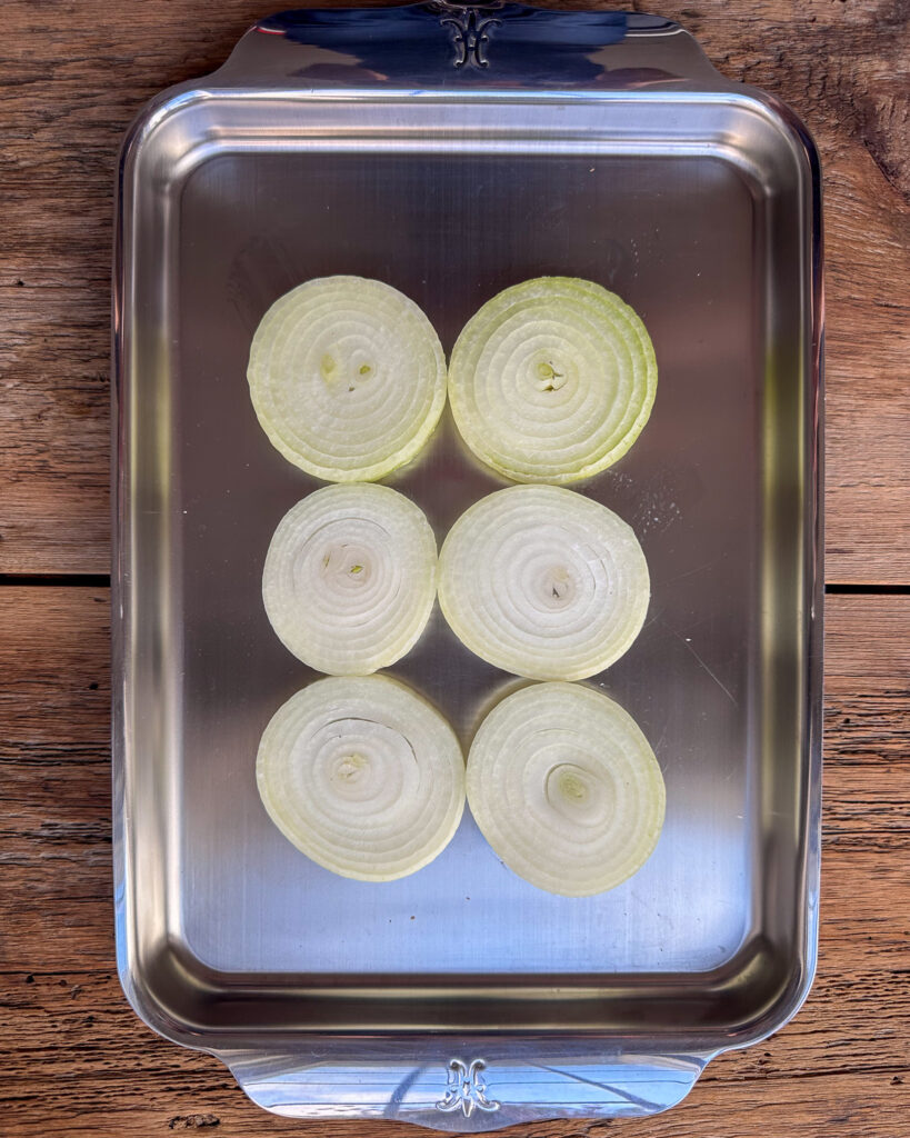 Slice a bed of onions on a tray for grilling.