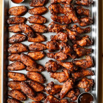 A sheet pan of chicken wings. One half are the flats, the are are the drumsticks.