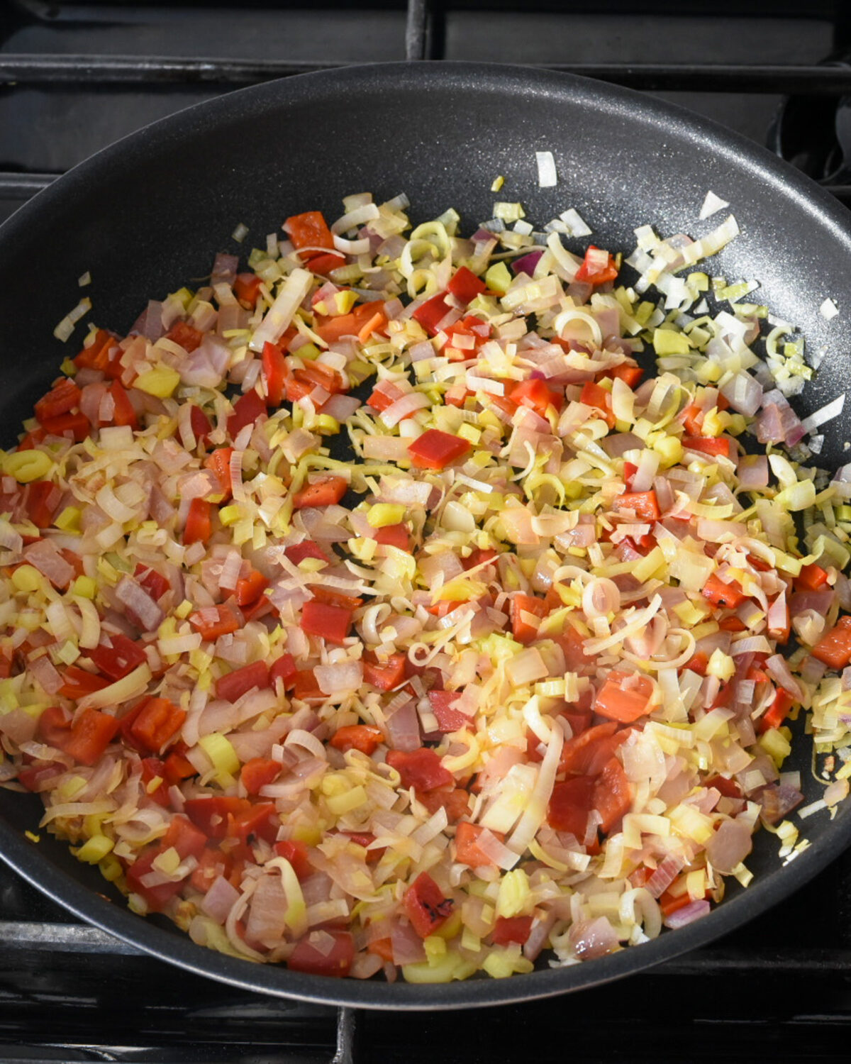 A pan of onions, leeks, and red peppers cooked until just soft, 
