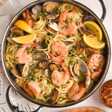 A top down image of a pot of Spicy Linguine with Clams and Colossal Shrimp.