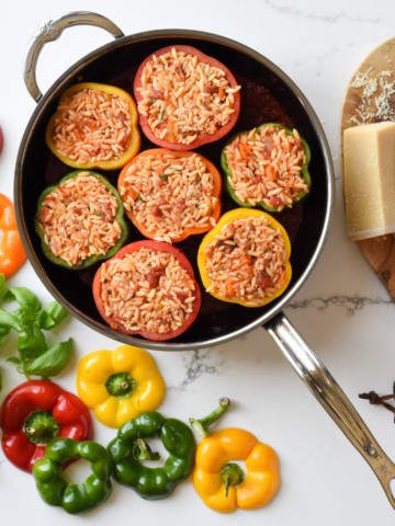 A top down image of a pan with seven Stuffed Peppers in Tomato Sauce