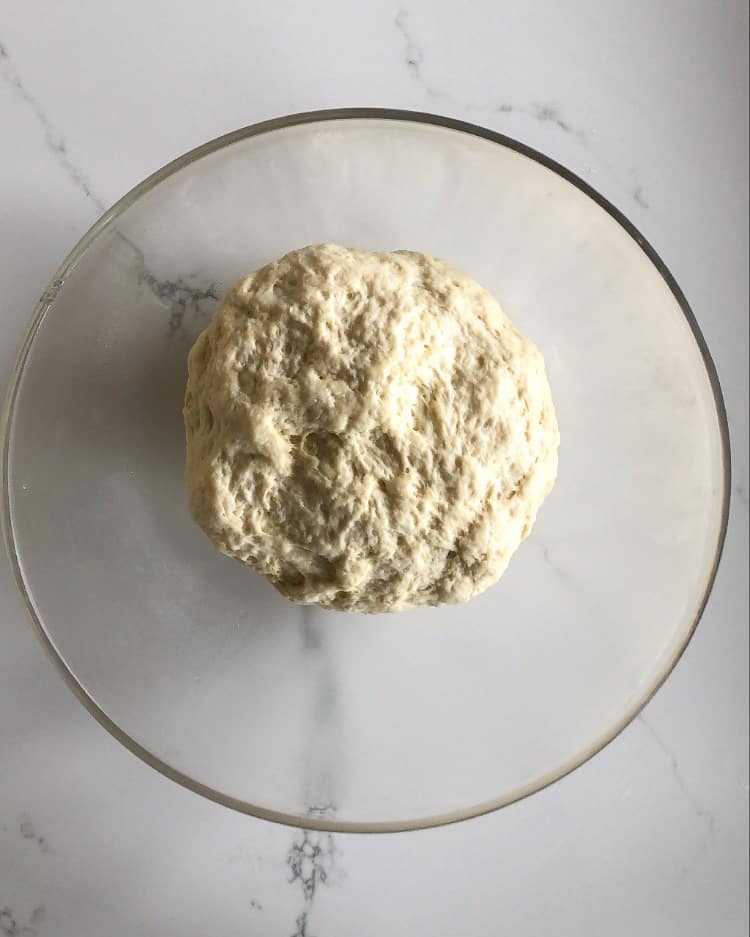 A medium ball of flatbread dough in a glass bowl.