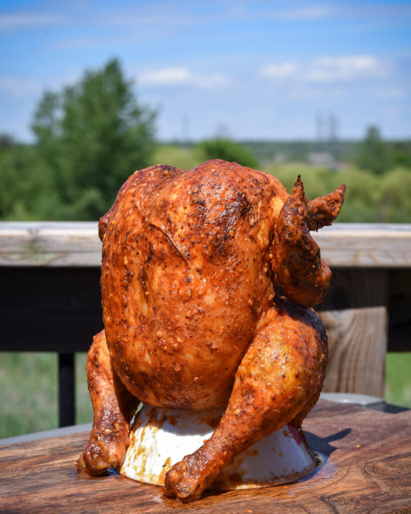 A crispy, golden beer can chicken sitting on a thrown.