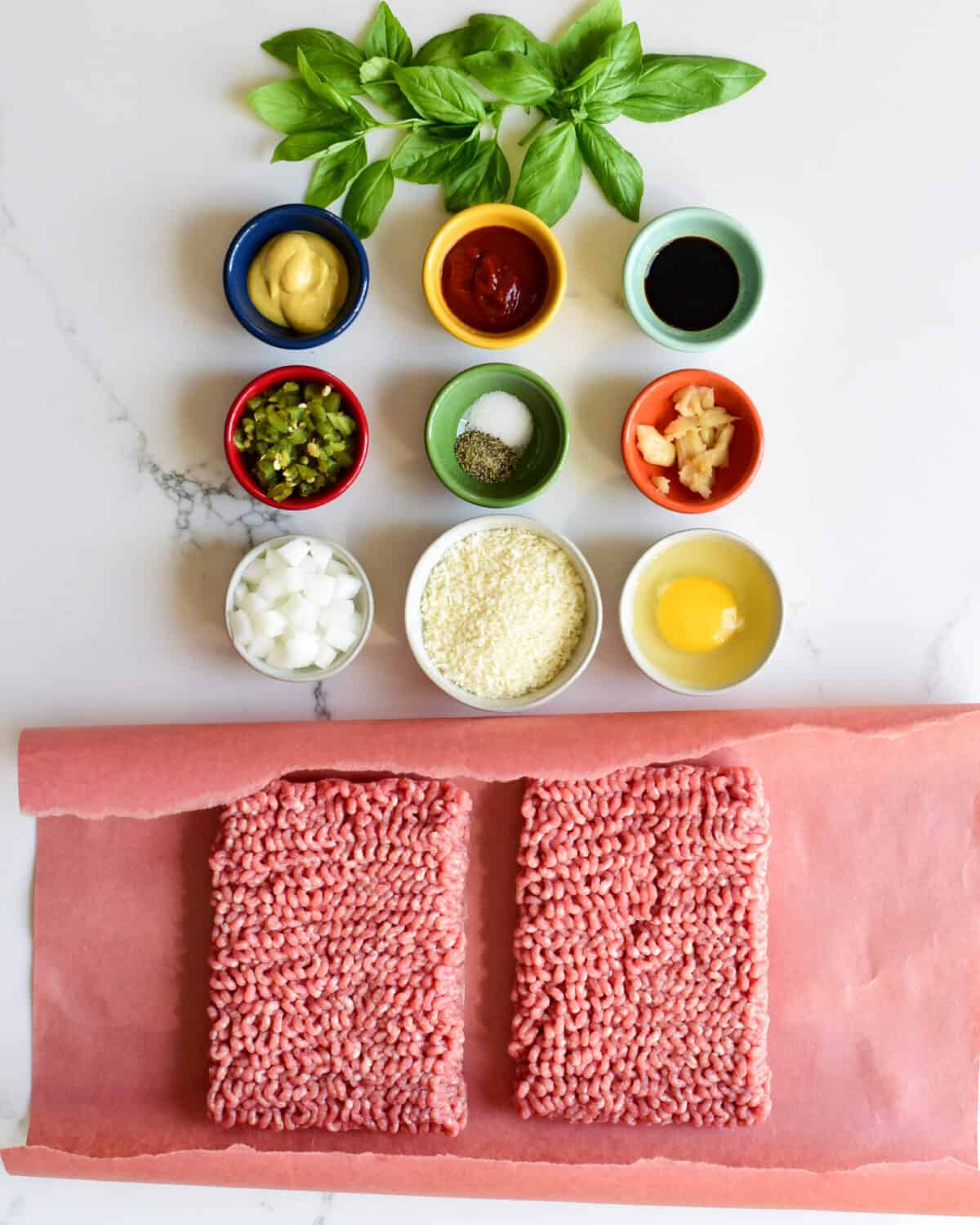 A top down view of ingredients for a Bahn Mi inspired pork burger which include nined small bowls of dry and wet ingredients and fresh ground pork.
