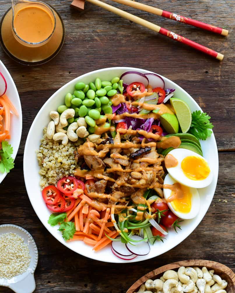 A colourful chicken grain bowl with peanut sauce, boiled eggs and veggies.
