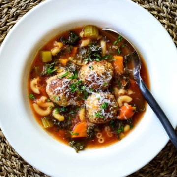 A top down view of a hearty Meatball Soup sprinkled with parmesan.