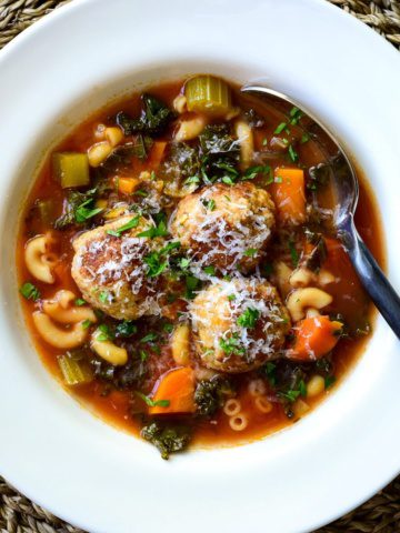 A top down view of a hearty Meatball Soup sprinkled with parmesan.