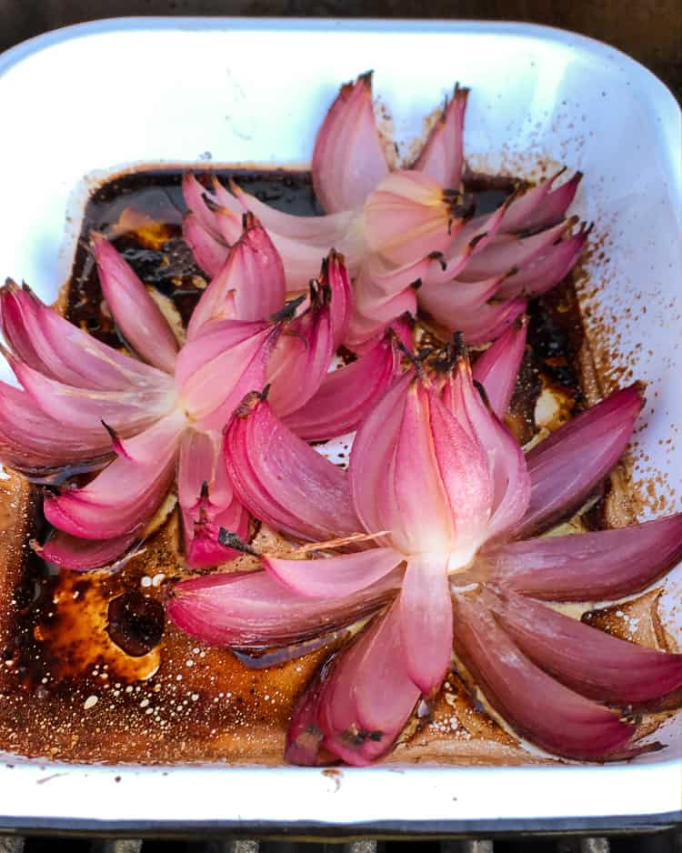 Roasted red onion flowers in a roasting pan. 