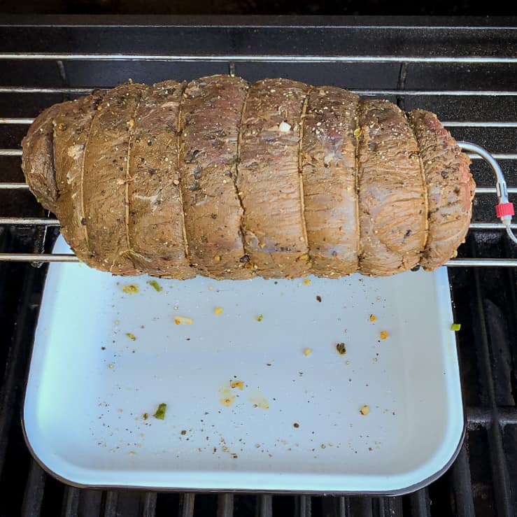A (raw) beef roast on the top rack over the portion of the grill that is not on. A drip pan placed under the roast.