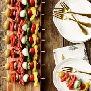 A long narrow board holds a row of colourful antipasto skewers.