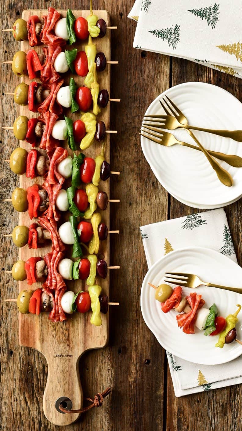 A long narrow board holds a row of colourful antipasto skewers.