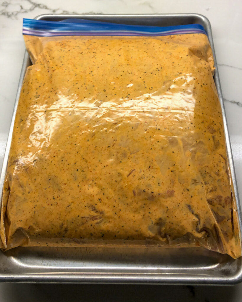 Chicken thighs marinating in a tikka masala sauce a sealed bag.