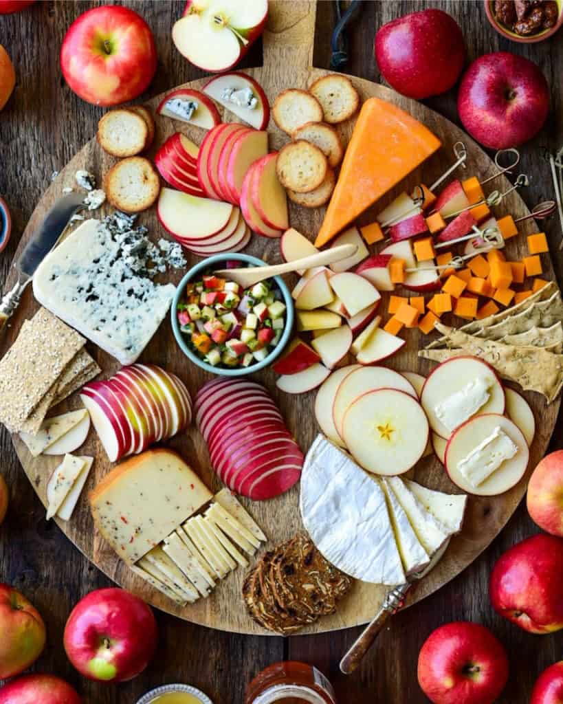 An apple and cheese board with various sliced apples and cheese.