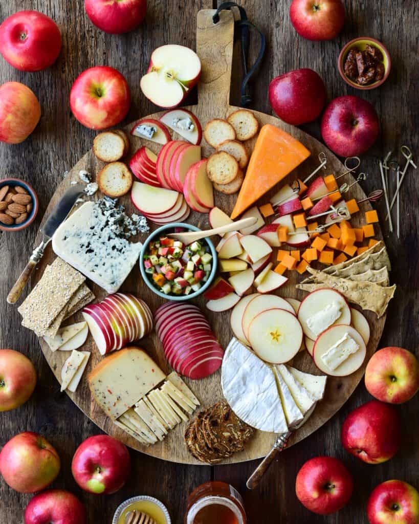 An apple and cheese board with various sliced apples and cheese.