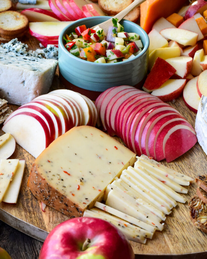 A close up of slices of McIntosh apples & smoked habanero cheese on a cheese board.