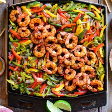 A square cast-iron skillet with fajita shrimp and vegetables.