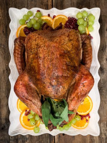 Roasted Turkey on a rectangular platter. Garnished with grapes, oranges and pomegranates.