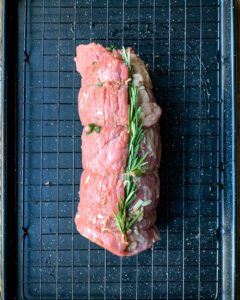 A rolled and tied up beef with a sprig of rosemary