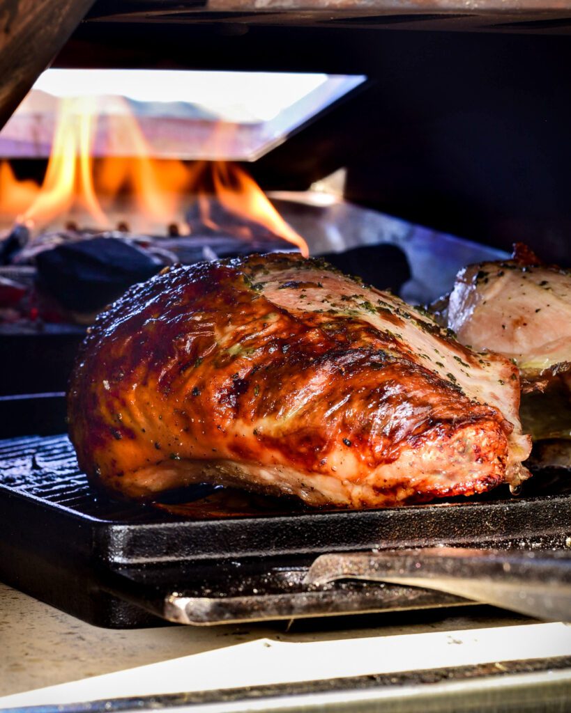 A beautiful golden turkey breast coming out a flaming Ooni oven.