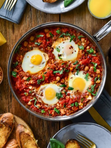 A top down image of a no bake shakshuka with four eggs in a skillet on a table ready to be served.