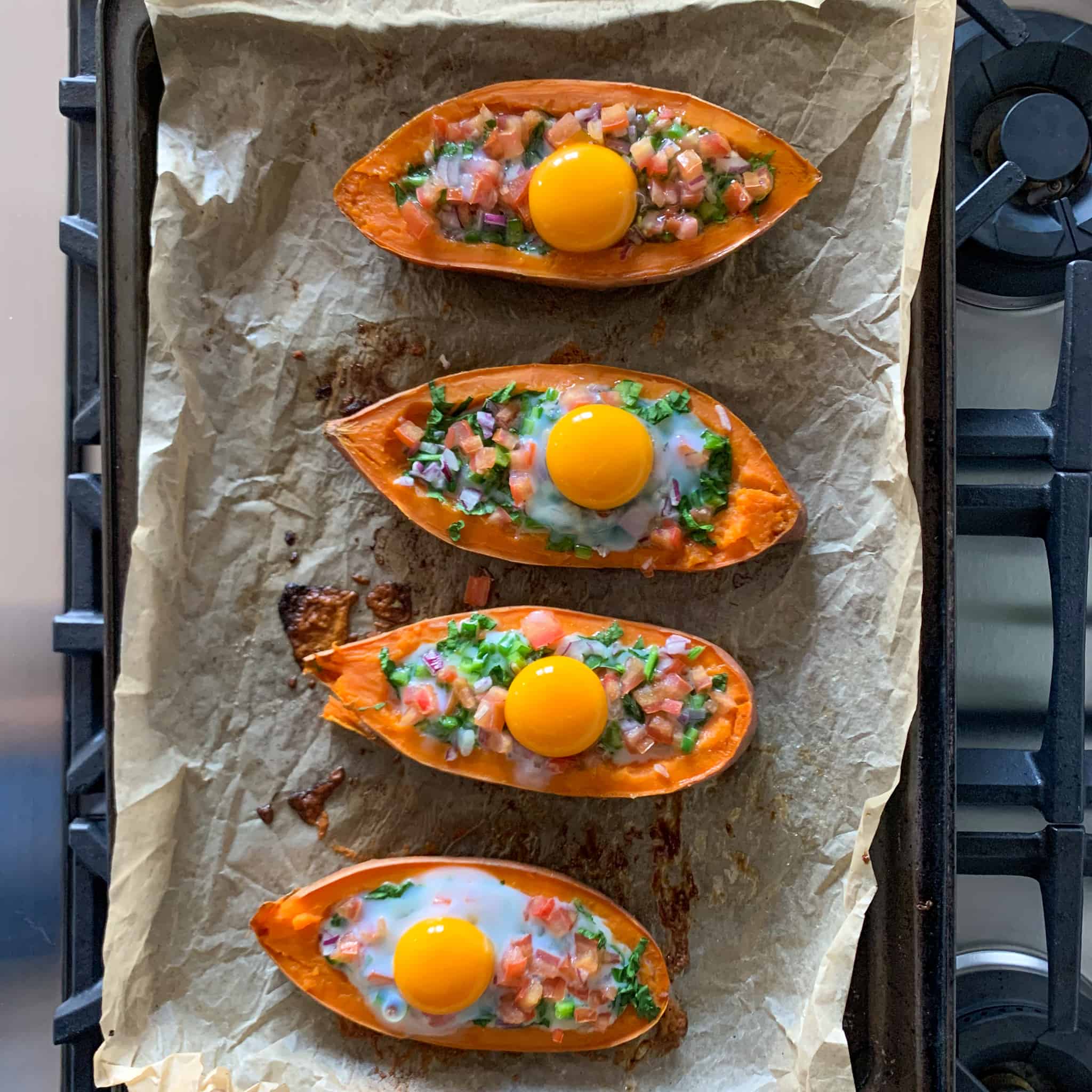 Sweet Potato Boats stuffed with veggies and an egg ready to go back into the oven.