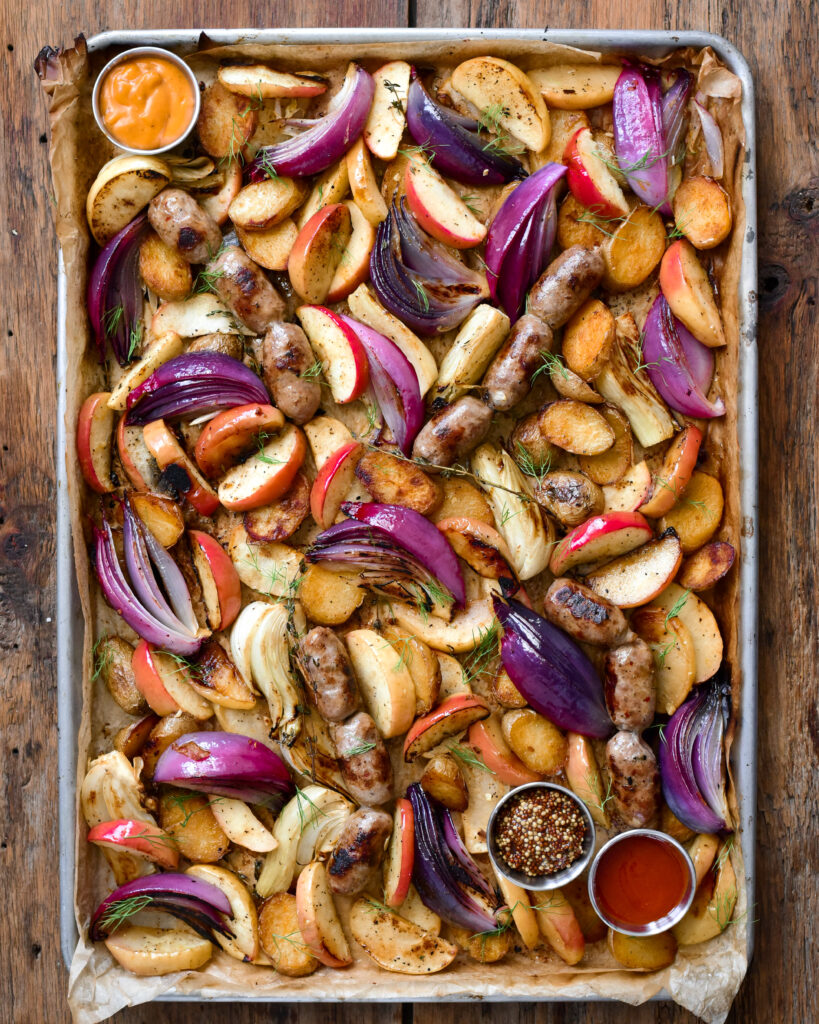 A sheet pan with roasted apples, fennel, onions and sausages.