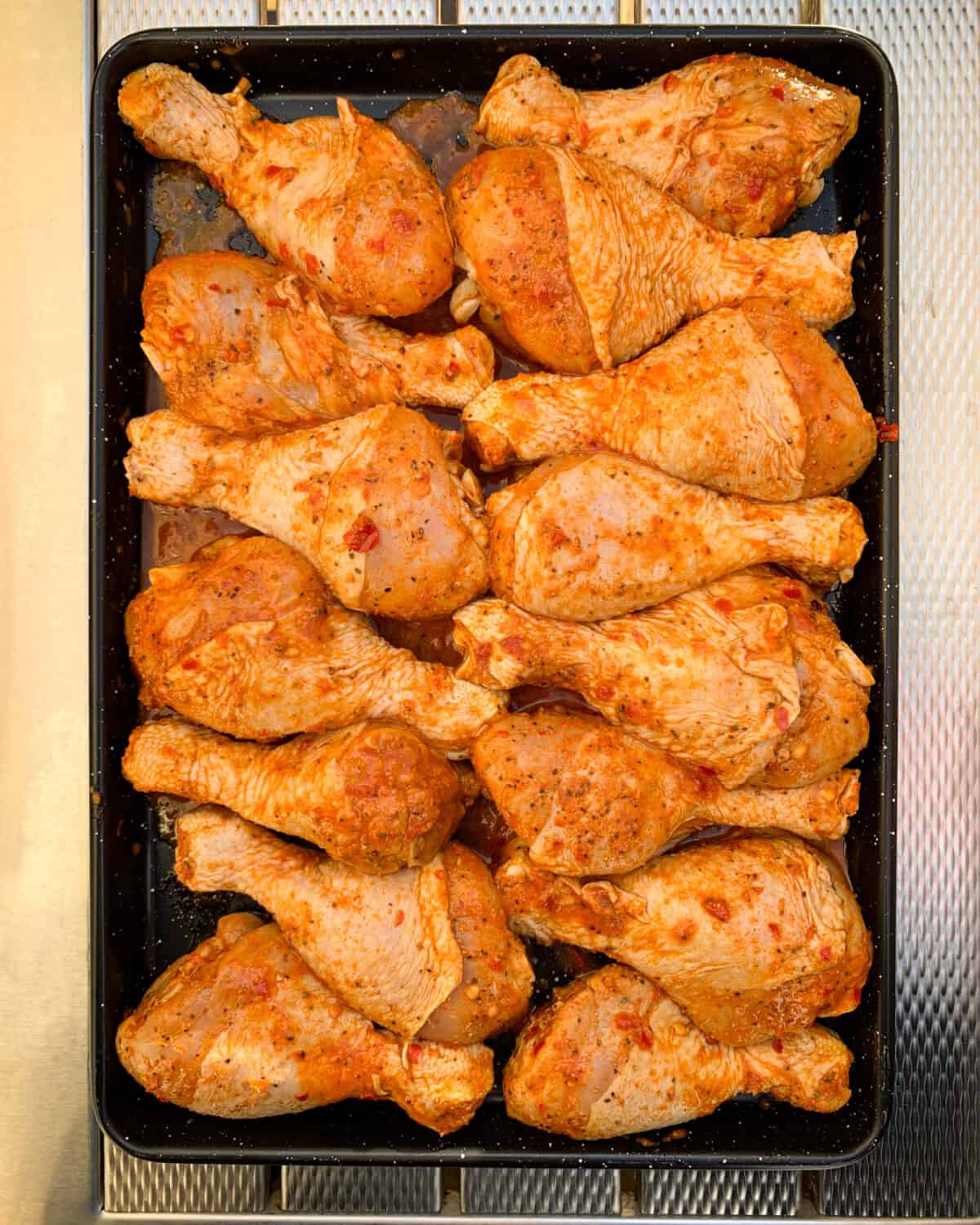 A tray of spicy chicken drumsticks marinating.
