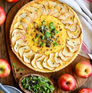 An apple quiche with a row of apples placed around the perimeter.