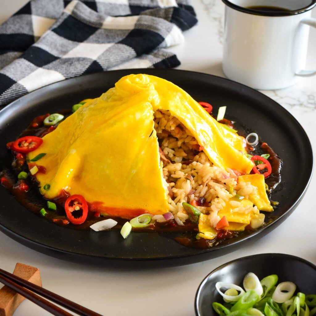A domed and swirled omelette over a pile of rice cut open showing the rice interior. 