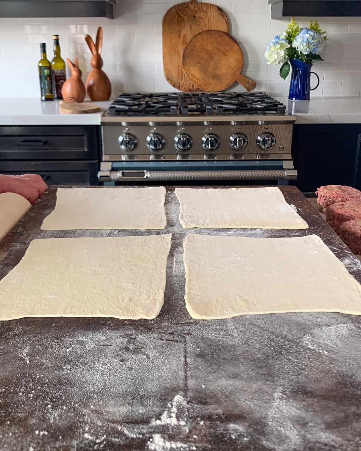 Roll out one sheet of the puff pastry on a lightly floured surface to a 12-inch square, then cut into 4 (6-inch) squares