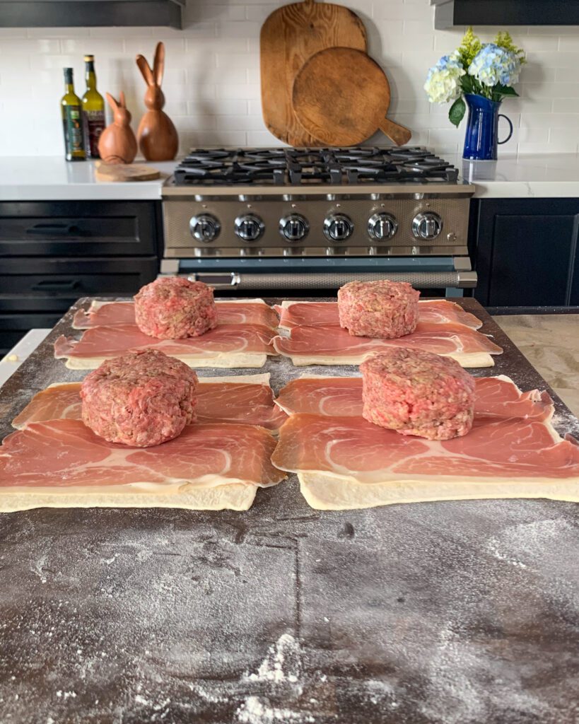 Add one beef patty on top of the prosciutto of each of the four squares