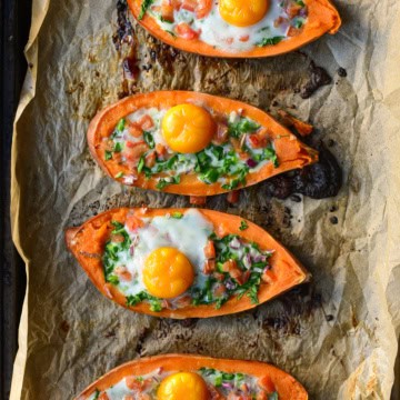 Four sweet potato boats with a cooked egg and vegetables.
