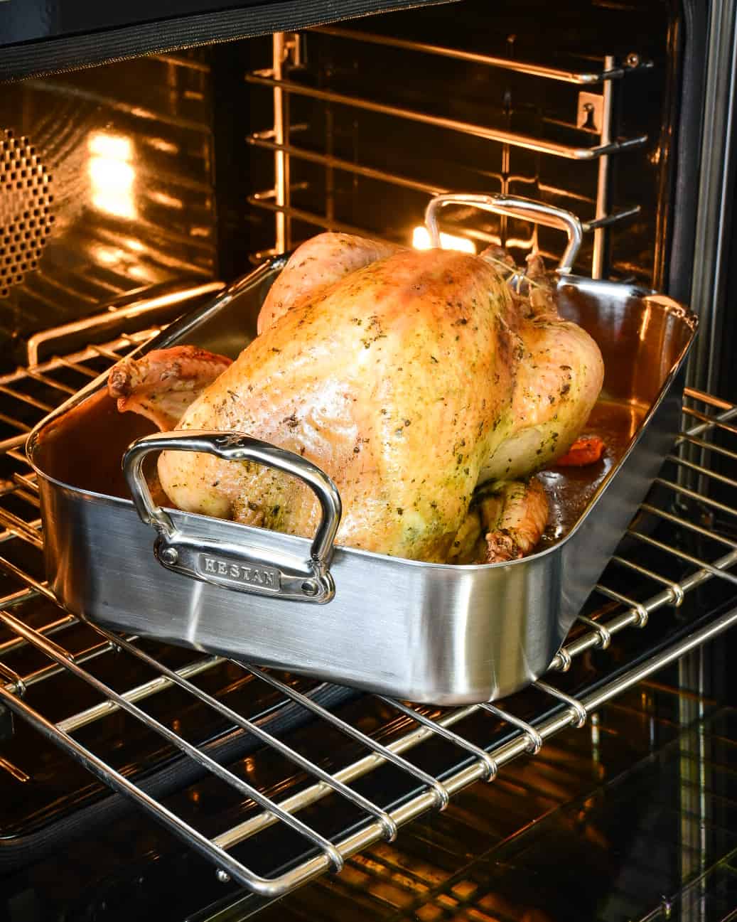 A golden roasted turkey in a roasting pan in the oven.