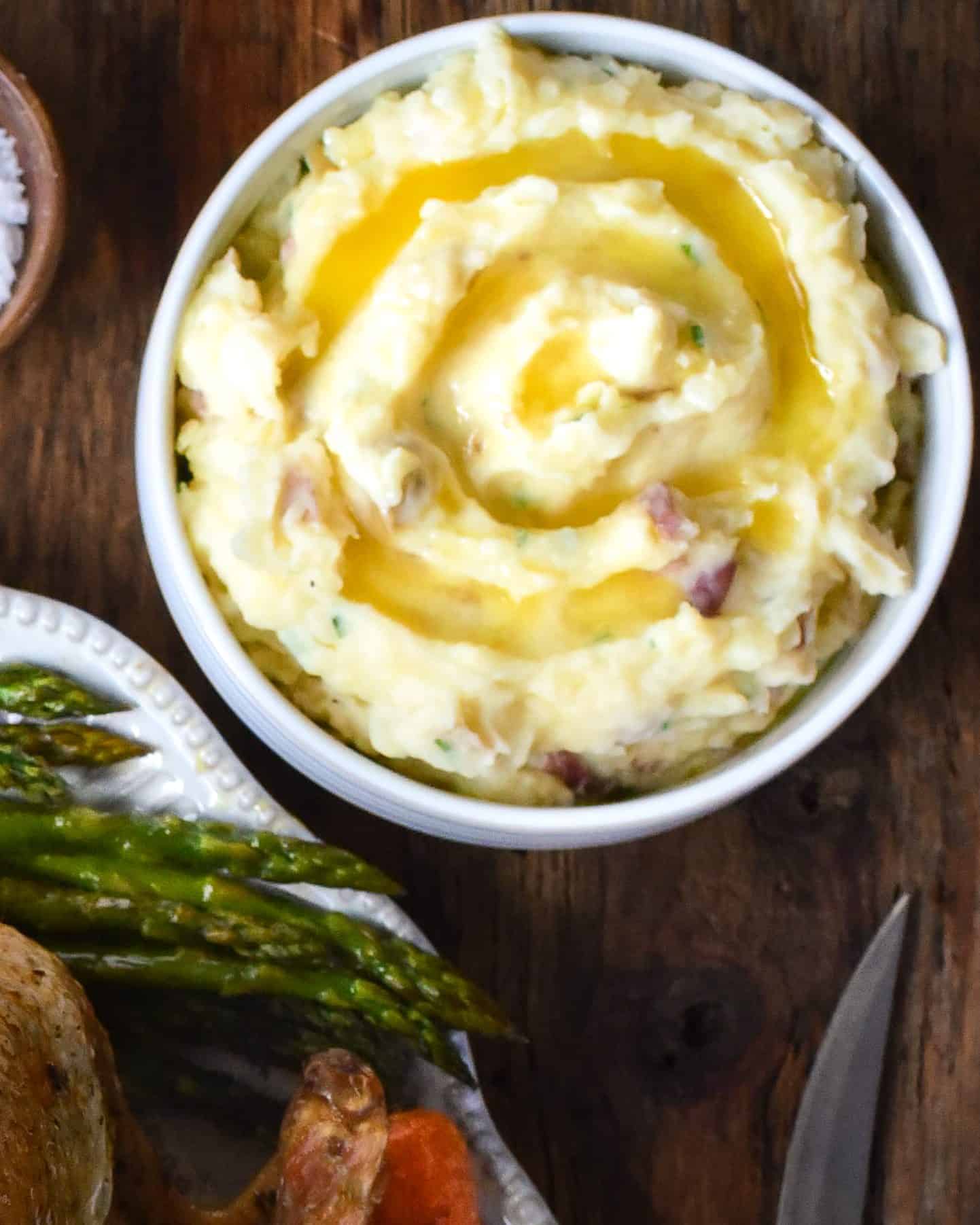 A bowl of mashed potatoes with a swirl of melted butter.