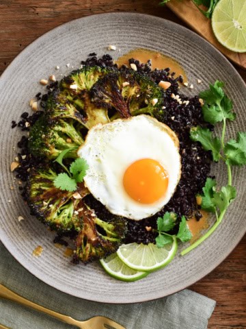 A serving of a stir-fried black rice with broccoli and a fried egg.