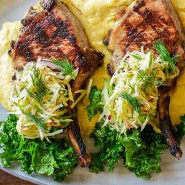 A pile of apple fennel slaw over two pork chops.