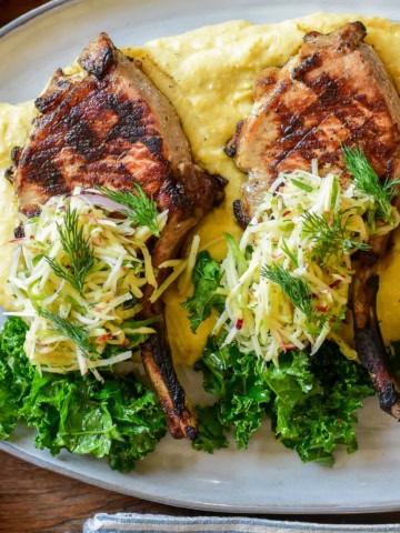 A pile of apple fennel slaw over two pork chops.