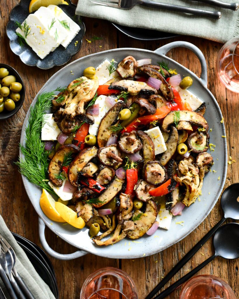 A round platter of  a Mediterranean Grilled Mushroom Salad with peppers, olives and feta cheese. 