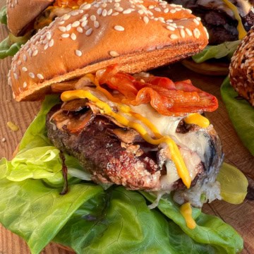A loaded mushroom, Pancetta and Asiago Burger with lettuce on a sesame seed bun.
