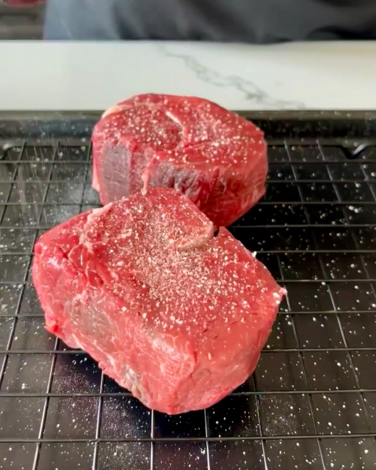 Two filet mignon steaks seasoned with salt.