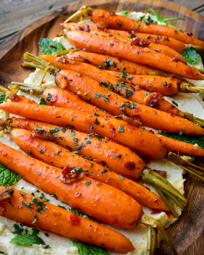 A platter of carrots on a bed of hummus.