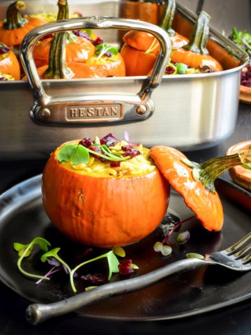 A Mini Stuffed Pumpkin with Wild Rice in front of a roasting pan.