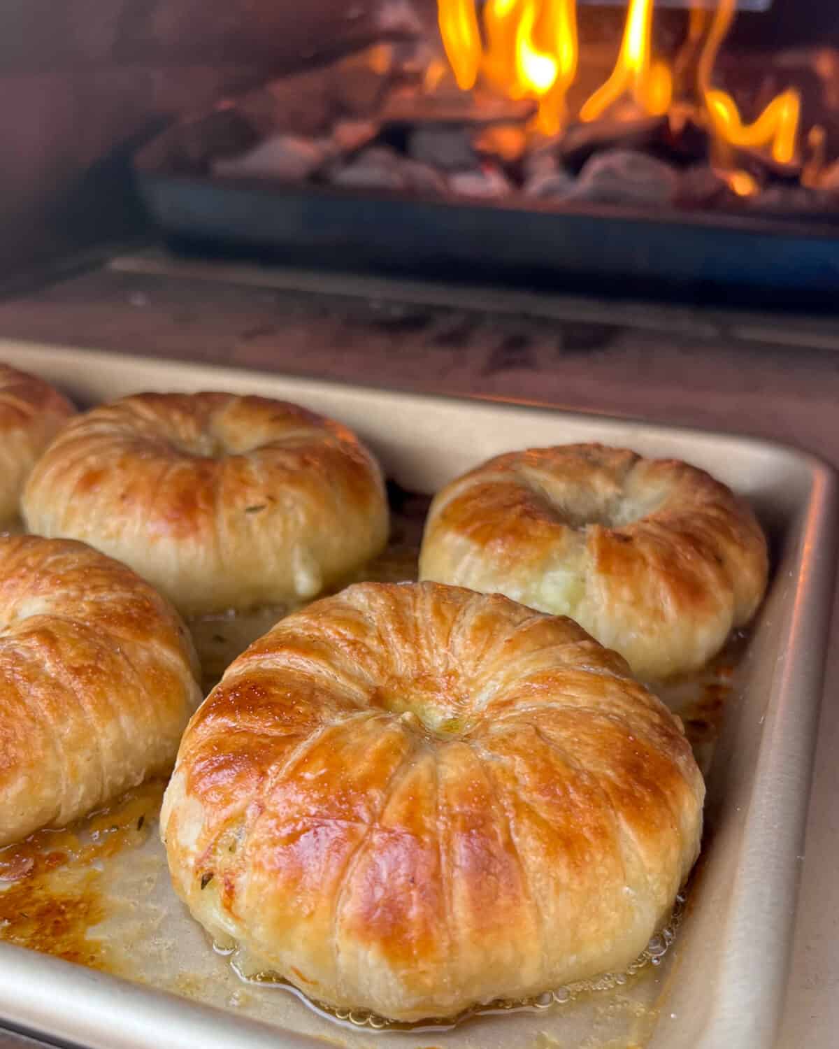 Savoury Apple-Brie Hand Pies in an Ooni with flames in the background.