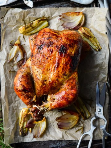 A golden brown rotisserie chicken on a sheet pan.